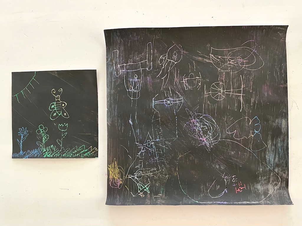 Crayon scratch art: butterfly in a garden and a Star Wars battle. They're made by coloring cardstock completely, painting with black poster paint, and scratching out designs to reveal colors.