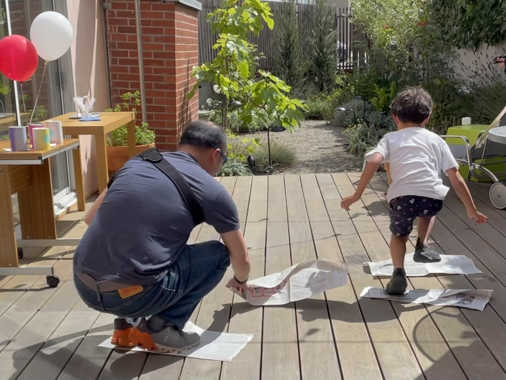 Dad and son do the newspaper relay race by setting down newspaper to walk on.