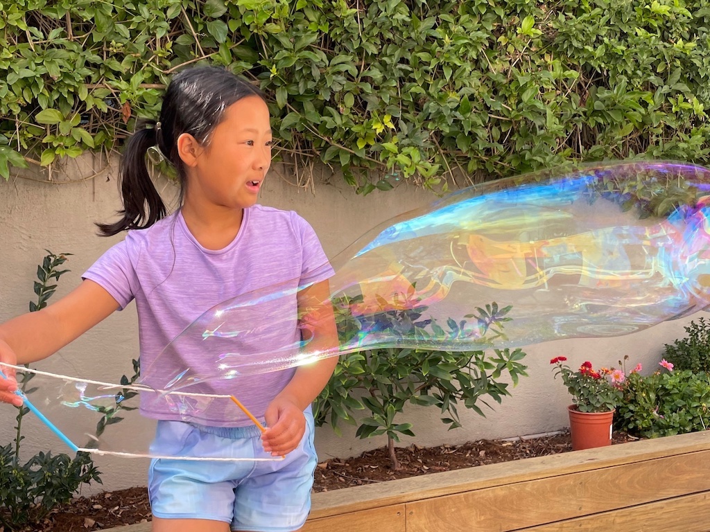 Child makes a giant bubble--it's a game interlude. 