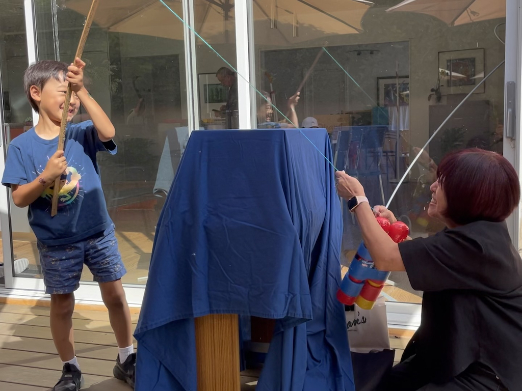 Child sends yardstick fishing line over the table; grandma clips a prize or trash to it in this fishing game.