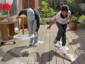 Mother and child playing a newspaper relay game.