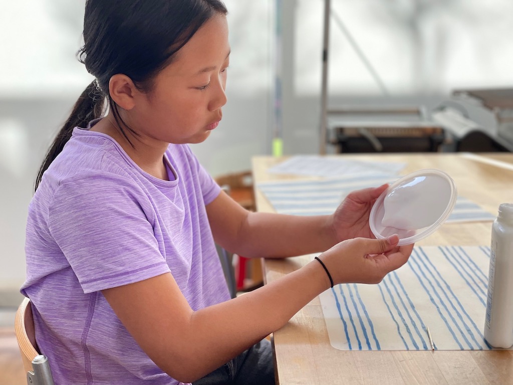 To make a suncatcher, start by spreading glue evenly over a plastic lid.