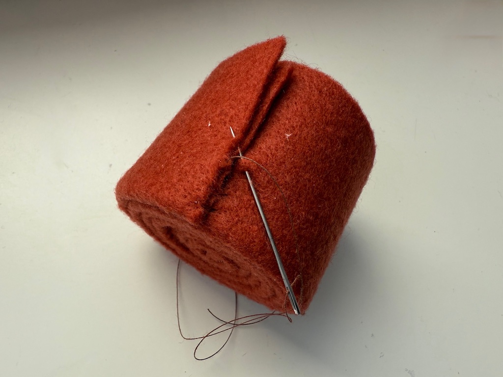 Stitch the end of the pumpkin strip to the rest of the felt roll to secure it.