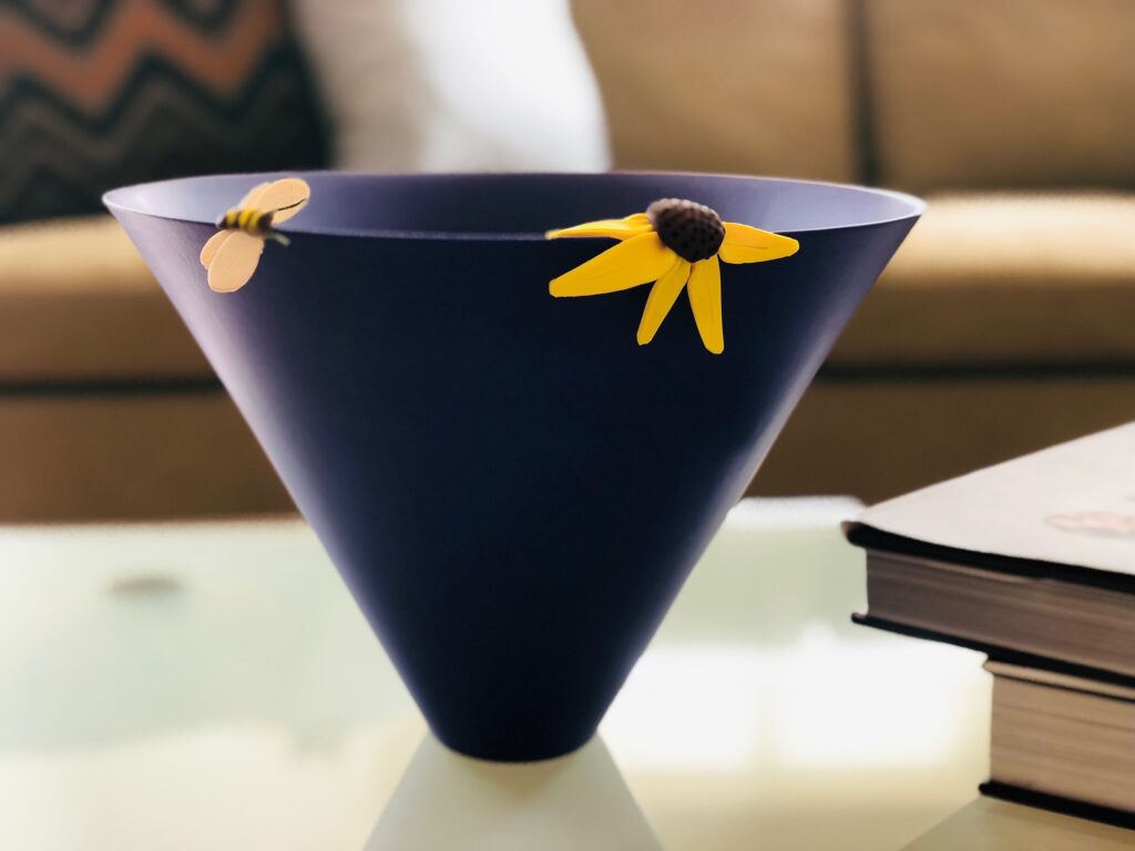You can use polymer clay to repair ceramics. Here, a bowl's chips were filled in with polymer clay and a sunflower and bee were crafted to hide the patches.