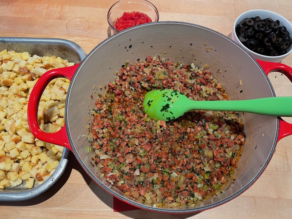 Pot shows linguiça, giblets, onion, celery, and parsley cooked together to start the Portuguese Thanksgiving Stuffing recipe.