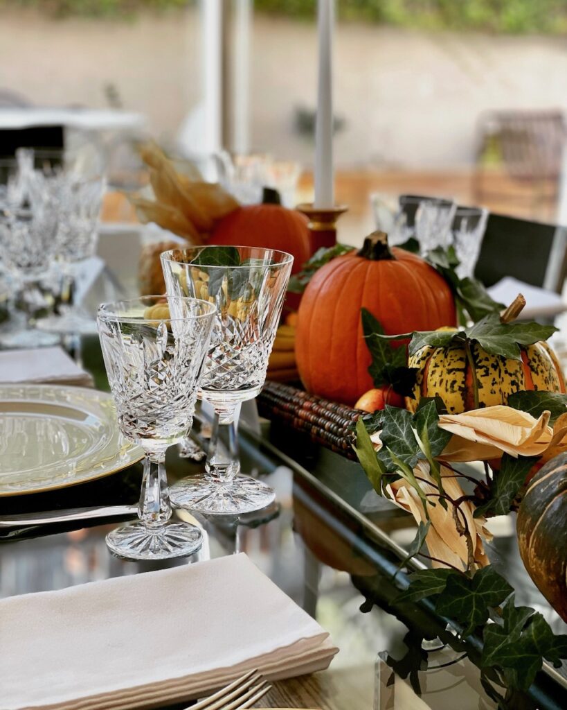 Pumpkins and other produce make up the table centerpiece; fine china, cut crystal, and silverware are used for this fancier version of the Thanksgiving table.
