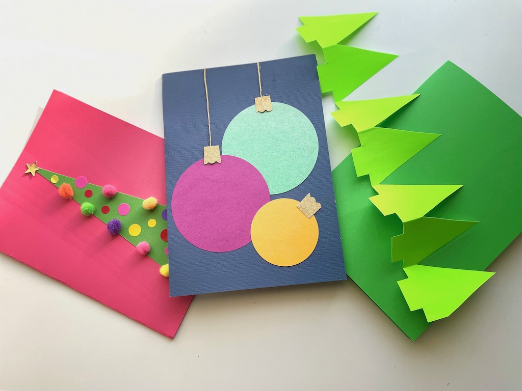 Give kids some sample card ideas: triangle with pompoms and stickers make a Christmas tree. Hole punched circles become Christmas ornaments. Accordion-fold trees present many design opportunities.