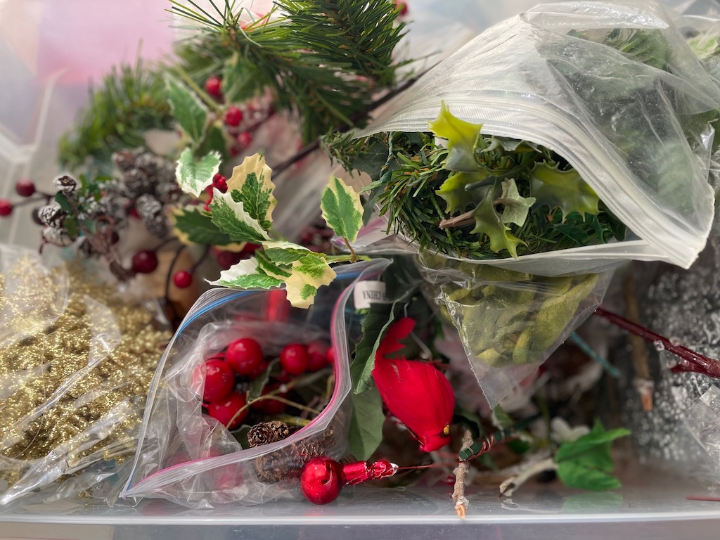 A binful of Christmas decorations for wreath-making.