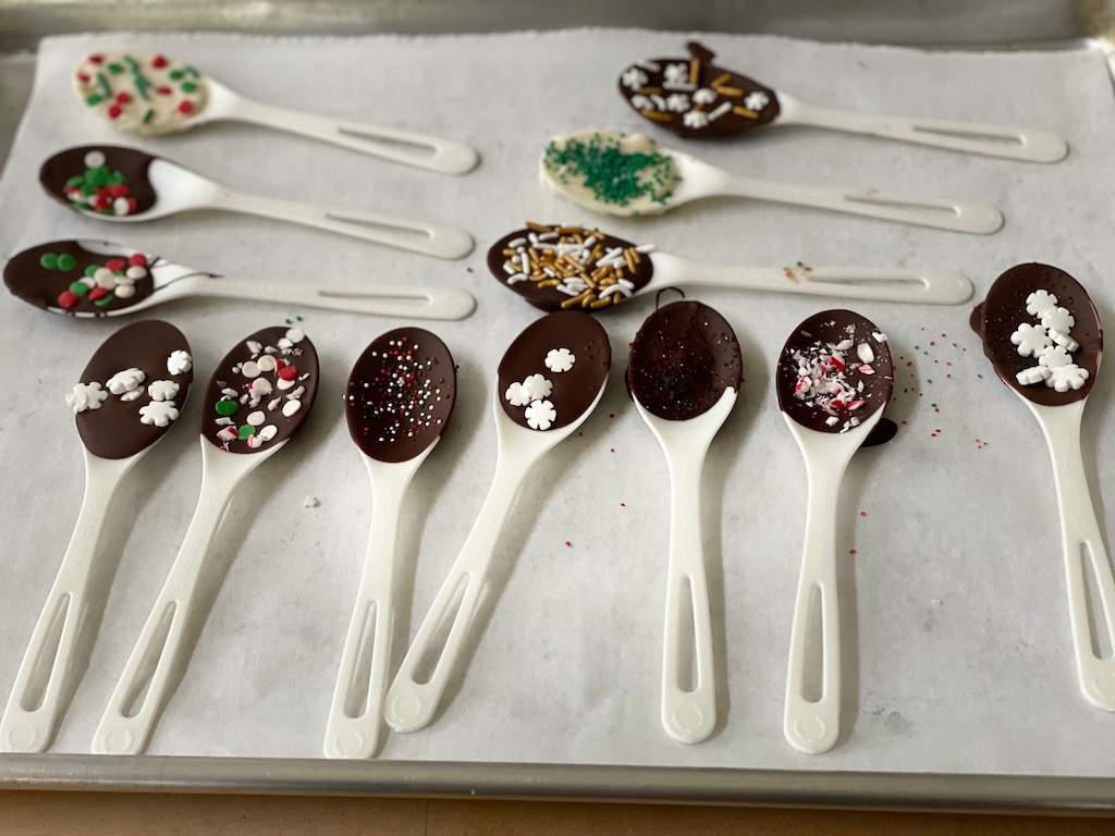 Hot Cocoa Stirring Spoons are disposable spoons dipped in chocolate and decorated with sprinkles for a welcome DIY Christmas gift.
