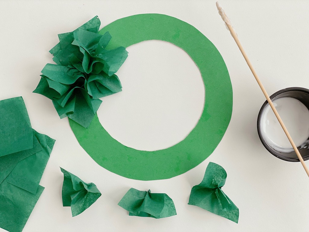 Tissue paper squares are pinched in the center to fluff, then applied to cardboard ring with with white school glue.