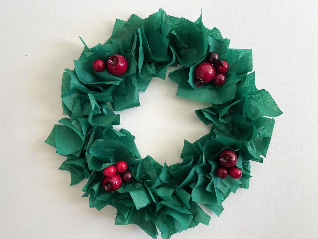 Tissue paper wreath with artificial holly berries.