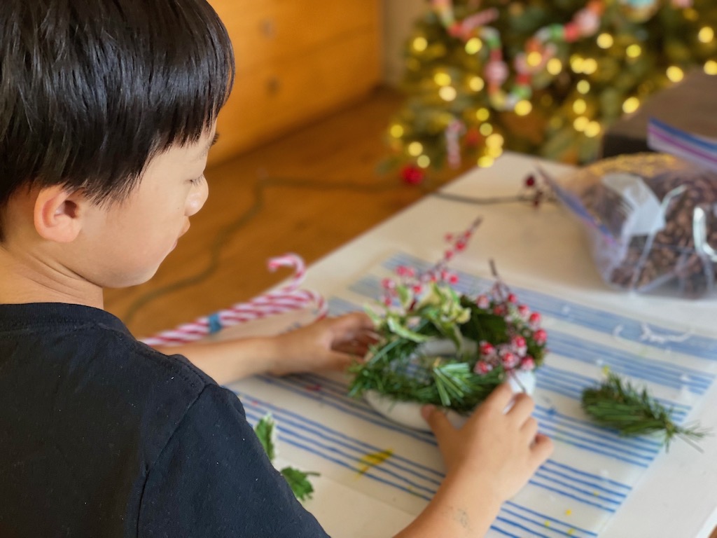 Child makes a wreath using a styrofoam ring base.