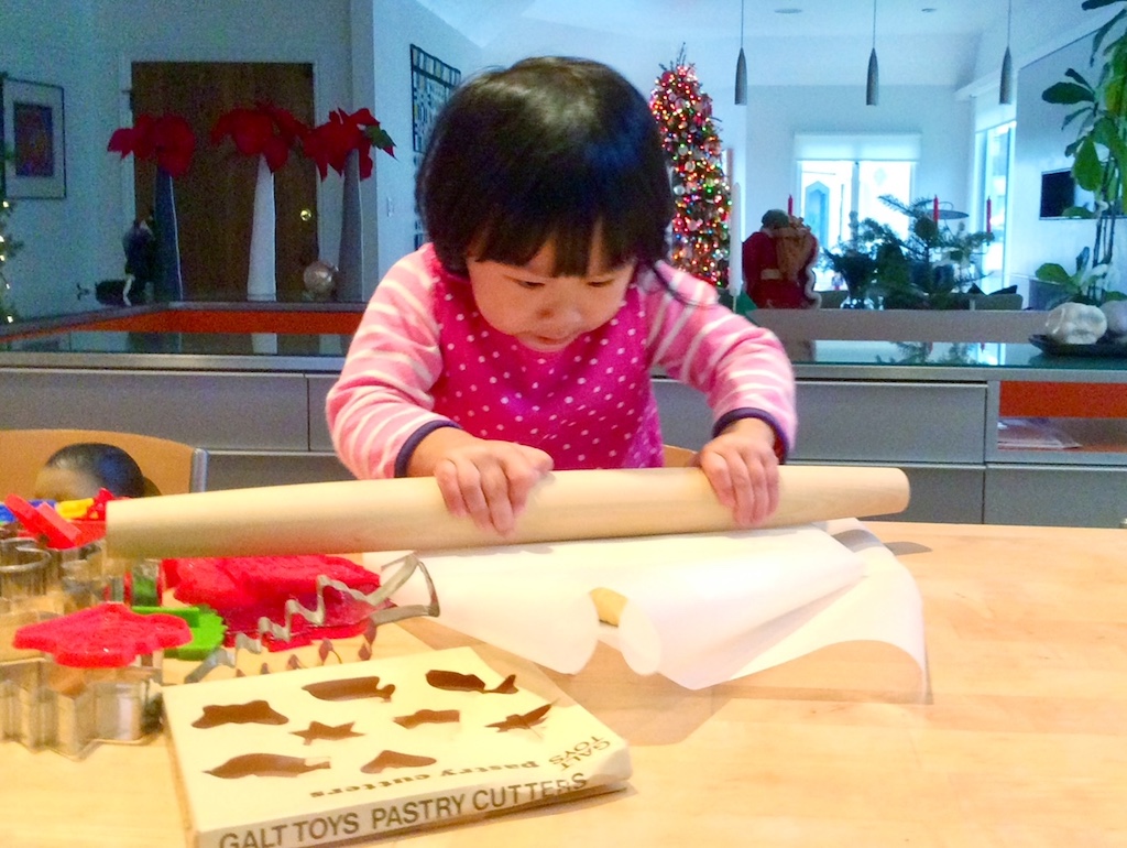 Child rolls out cookie dough. Grandkids as young as three can do activities in the kitchen.