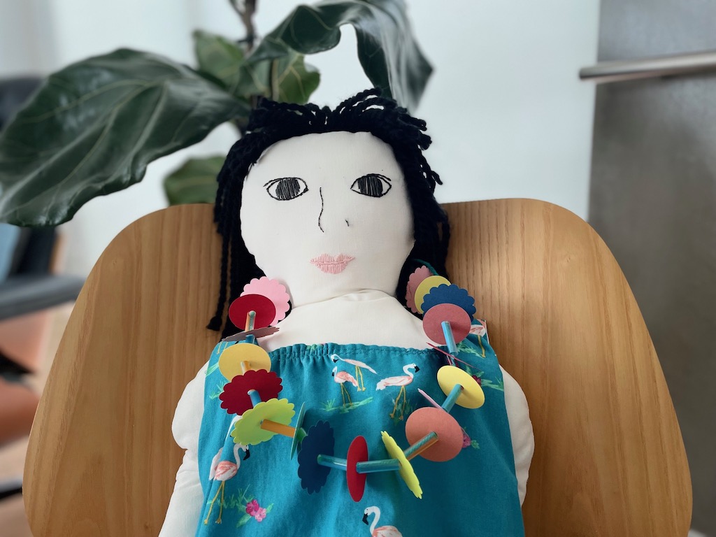 Life-size homemade doll models a construction paper lei that kids can make for a luau.