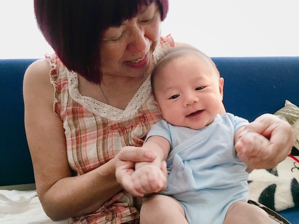 Grandma claps baby's hands to the beat of a rhyme to entertain a fussy baby.