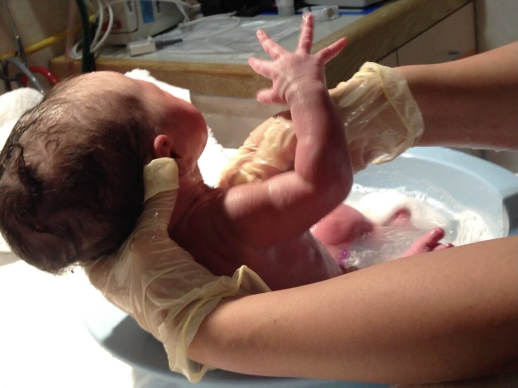 Newborn having her first bath. Grandparents can help to document the first hours of a grandchild's life through photography and videos.