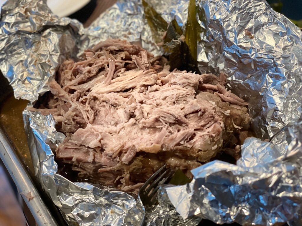 Kalua pig, right from the oven, is shredded with two forks.