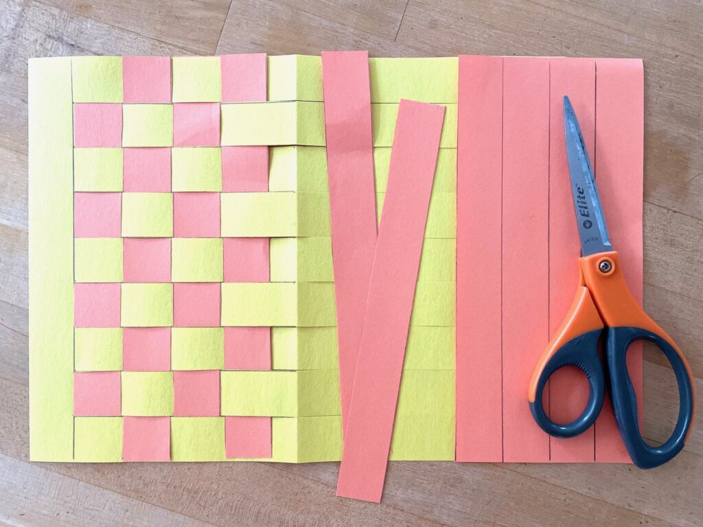 Cut 1-inch strips from a second sheet of construction paper and weave them into the backing.