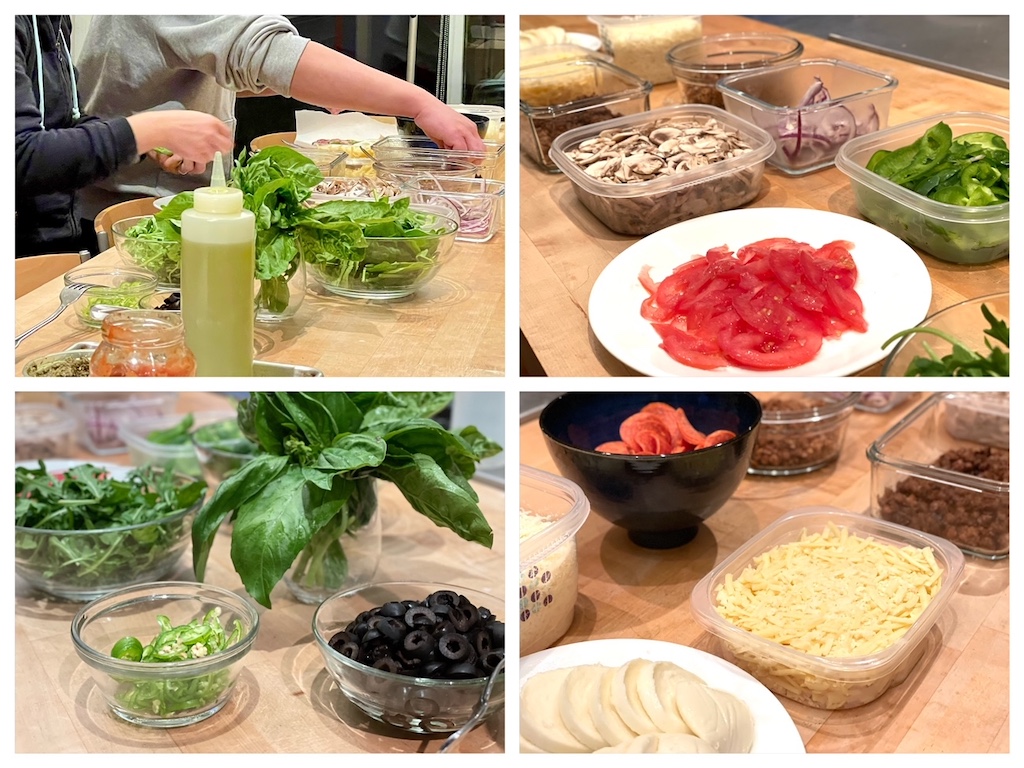 Toppings for make-your-own pizzas include sliced tomatoes, mushrooms, basil leaves, arugula, olives, and mozzarella cheese.