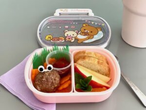 A single meatball with fruit slices and carrot flowers make a preschooler's bento.