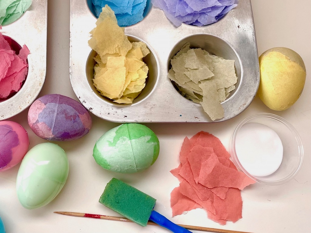 Coat plastic eggs with white glue and smooth tissue paper pieces on the eggs until the eggs are covered completely.