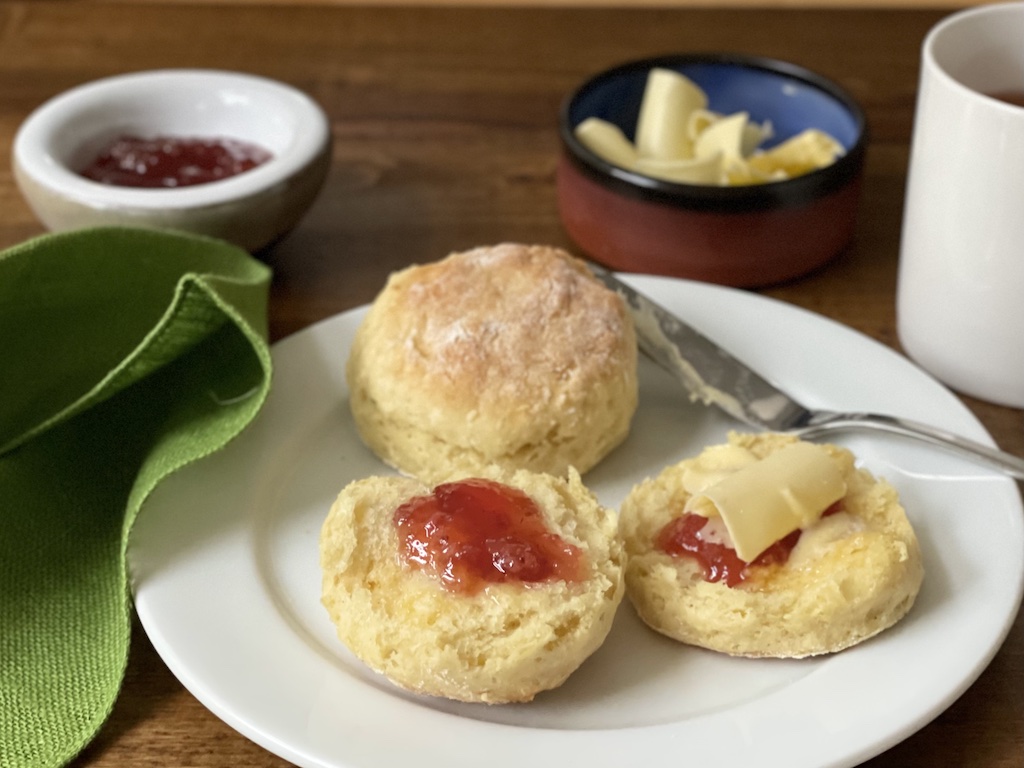 Home-baked Irish scones with strawberry jam and butter curls are ready to eat, warm from the oven.