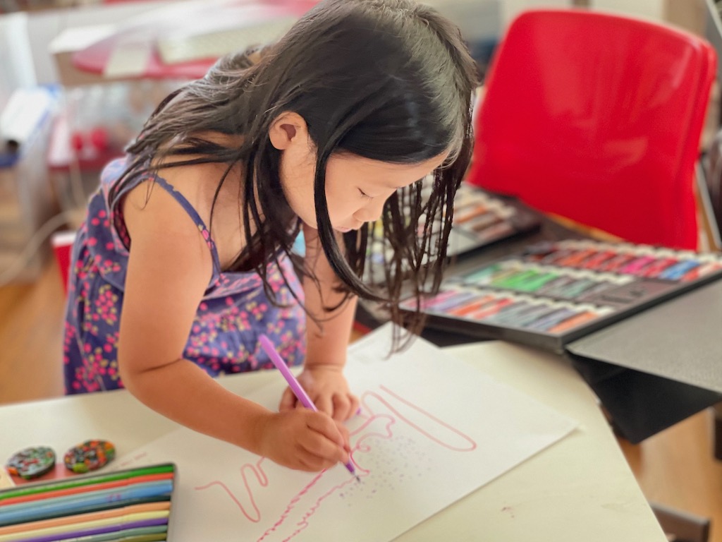 Child listens to music and expresses the emotion with markers to create a work of art.