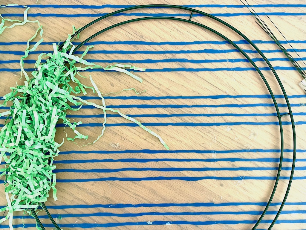 Wire clumps of Easter grass to the wire wreath ring to make the wreath base.