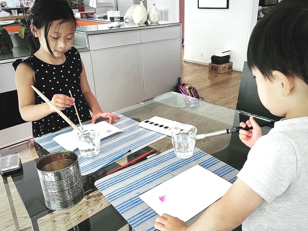 Kids dropping paint on water-covered paper to let the colors bleed.
