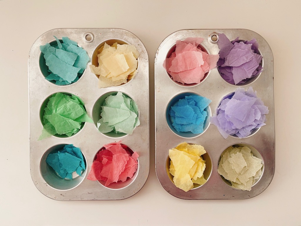 Torn bits of tissue paper can be organized in muffin tins to keep colors separate.