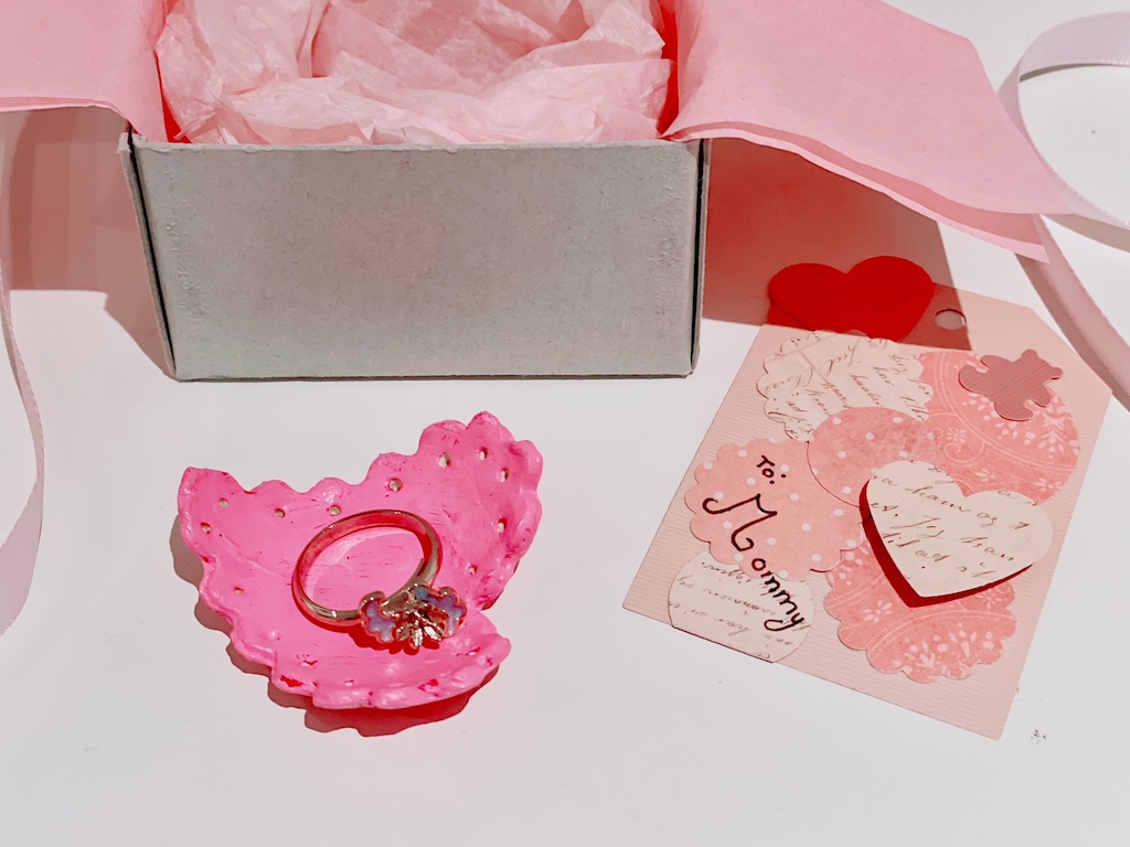 An air dry clay heart-shaped ring dish and handmade gift tag make a Mother's Day gift from a child.