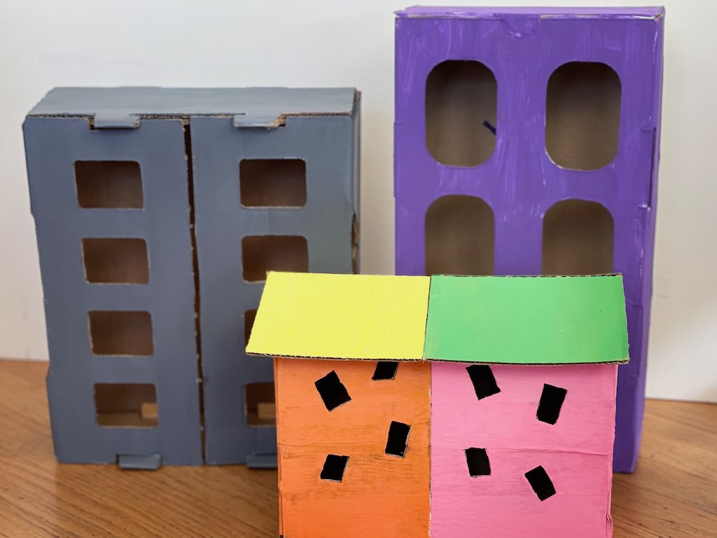 These toys from throwaways are made from cardboard boxes. The houses are made from small boxes; the condominiums from fruit boxes. They make great backdrops for kids playing with cars.