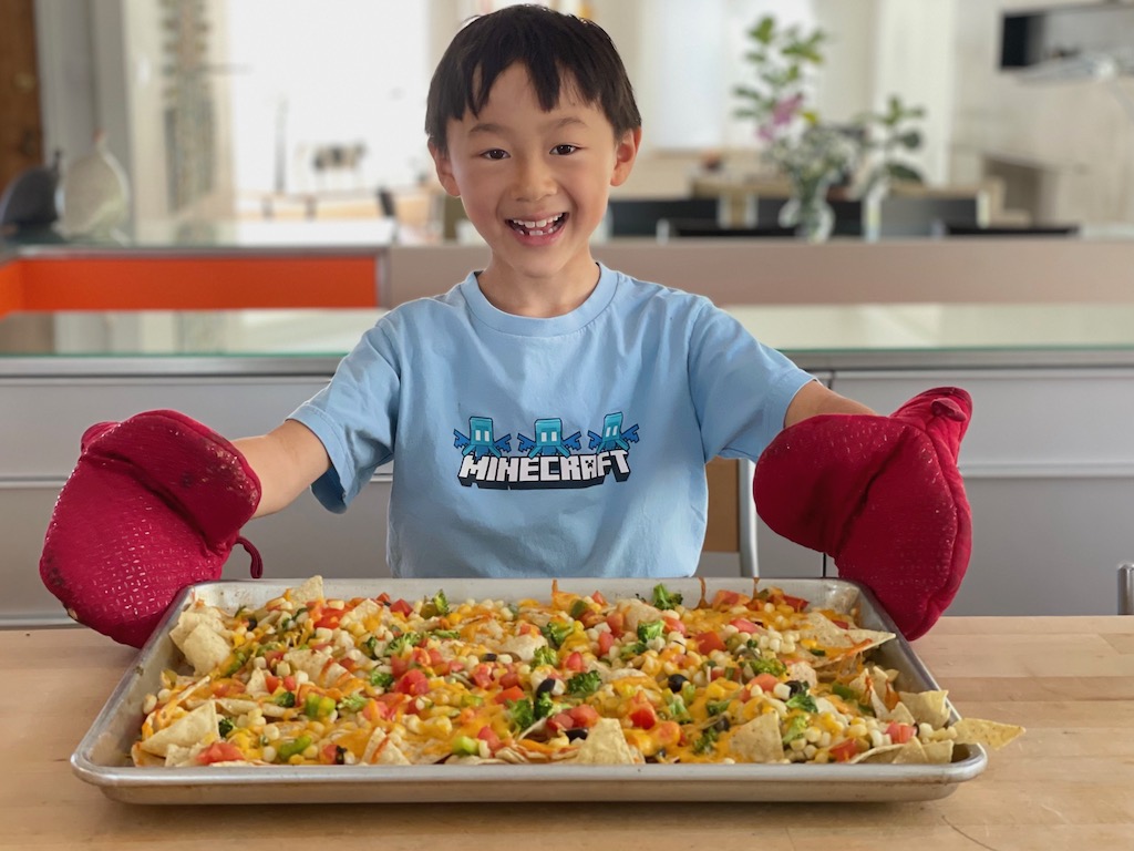 Child with a sheet pan of Healthy Vegetable Nachos that he made by himself.