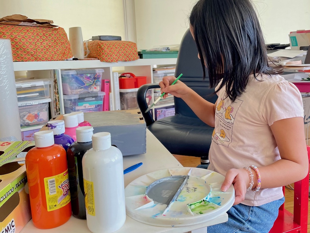 Child paints a cardboard box to make a condominium.