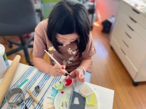 Child paints air dry clay to make a ring holder from air dry clay for a last-minute Mother's Day gift.