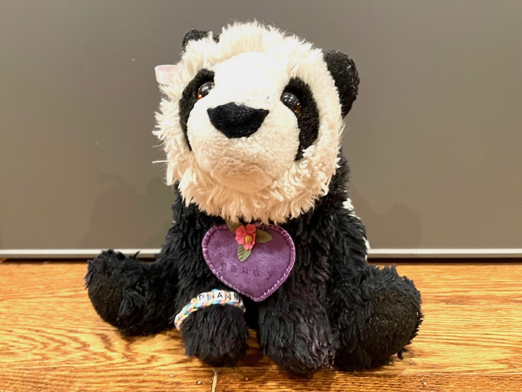 Child's stuffed panda wears a felt heart around the neck with an AirTag electronic tracker inside, to keep the stuffie from getting lost.