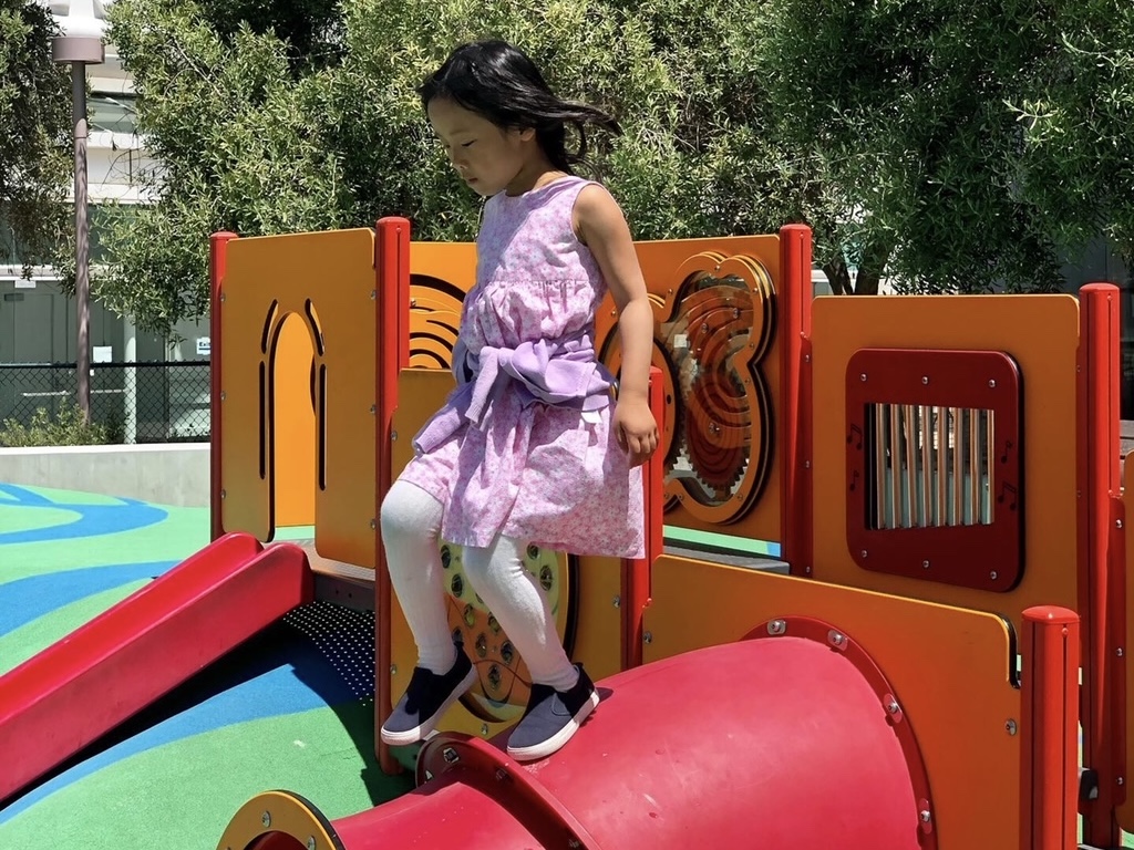 Child in a playground exploring play structures.