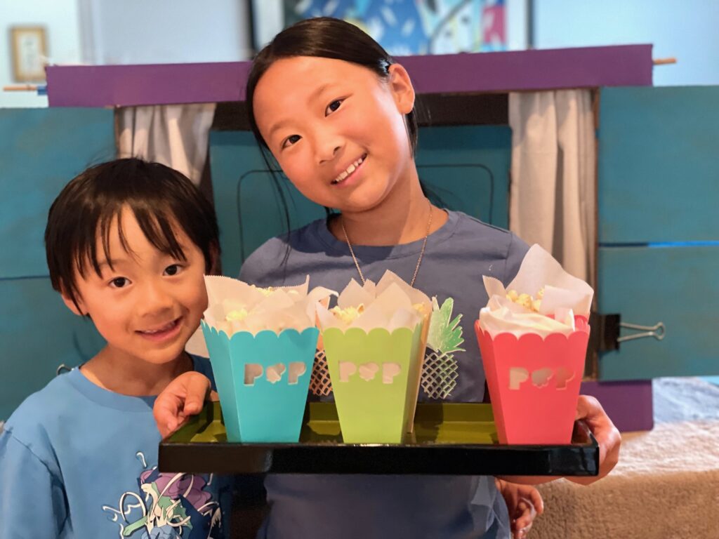 Kids offering the audience popcorn in popcorn boxes before the performance.