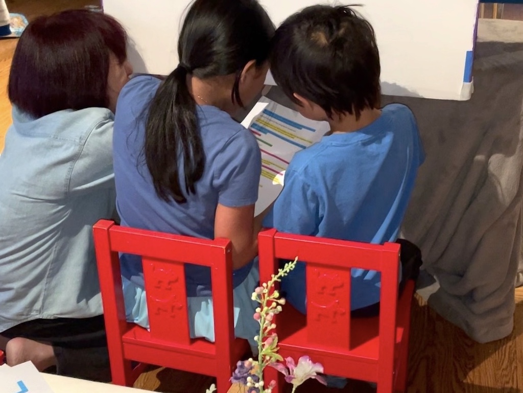 Grandma and grandkids reading the script while manipulating puppets from backstage.