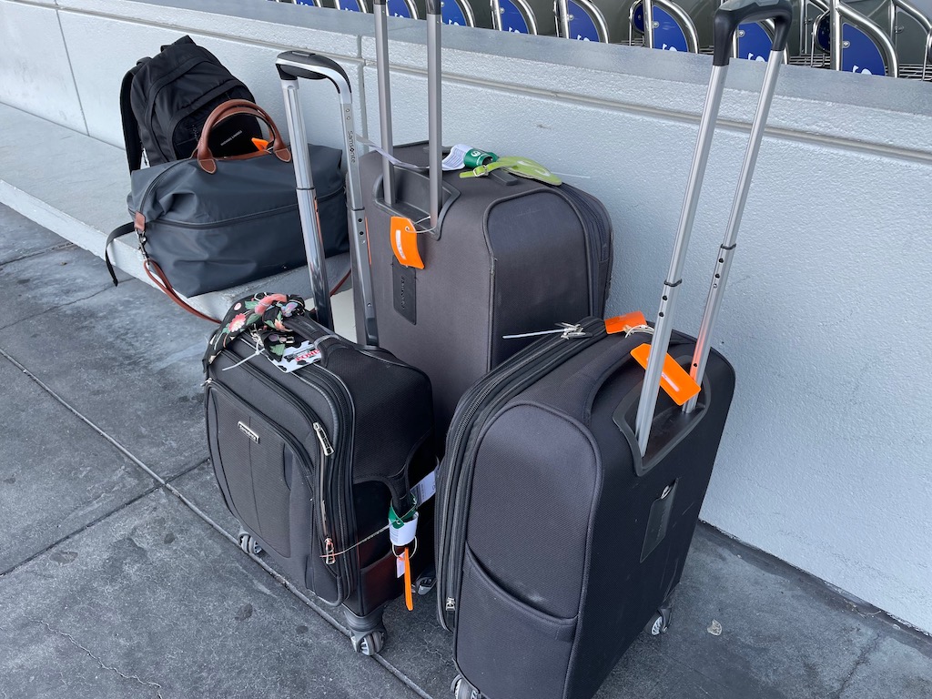 Suitcases at the airport: Two small rollers for the overhead, two bags for under the seat, and one to check.