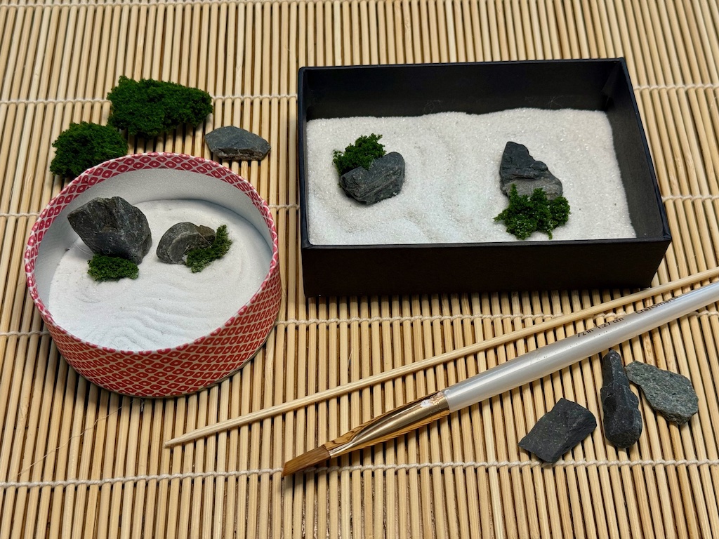 Two mini zen gardens with tools and materials.