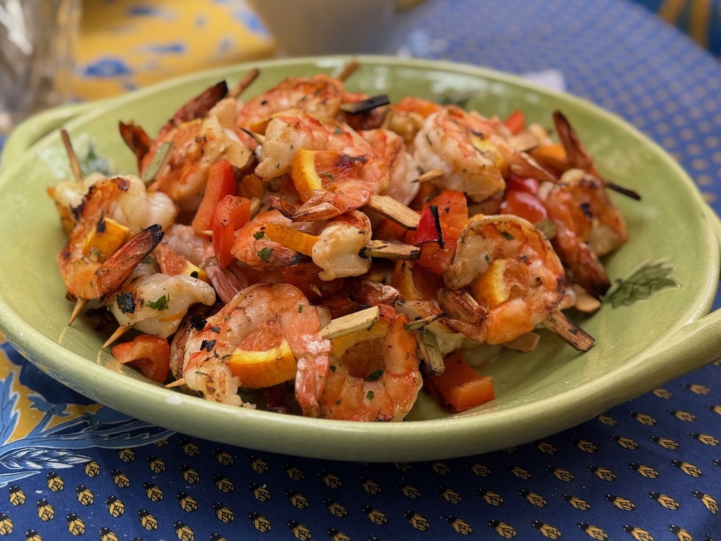 Marinated shrimp are threaded with an orange wedge on small skewers and grilled.