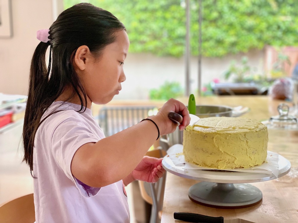 Child frosts a birthday cake for a family birthday party.