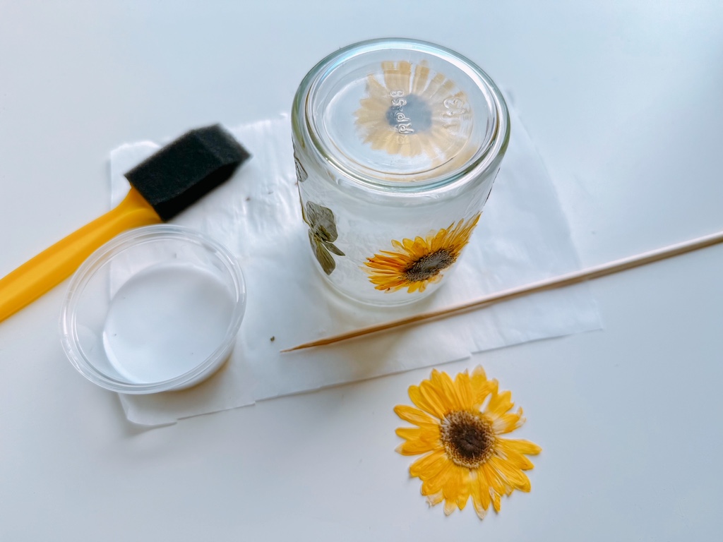All materials needed for pressed flower jars: foam brush, glue, jar, and pressed flowers.