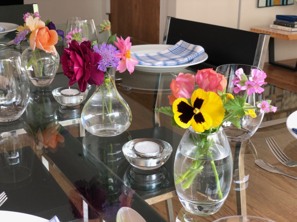 Assorted flowers in mismatched glass vases decorate the dinner table.