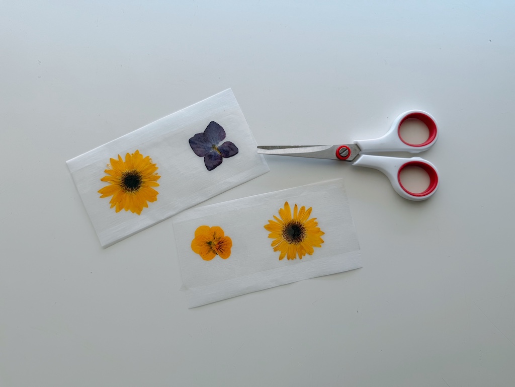 To make the stickers, lay pressed flowers on parchment paper, cover with clear tape, then cut out the flowers leaving a 1/4-inch margin.