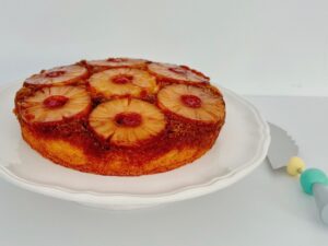 Pineapple upside-down cake is topped with canned pineapple slices and maraschino cherries.