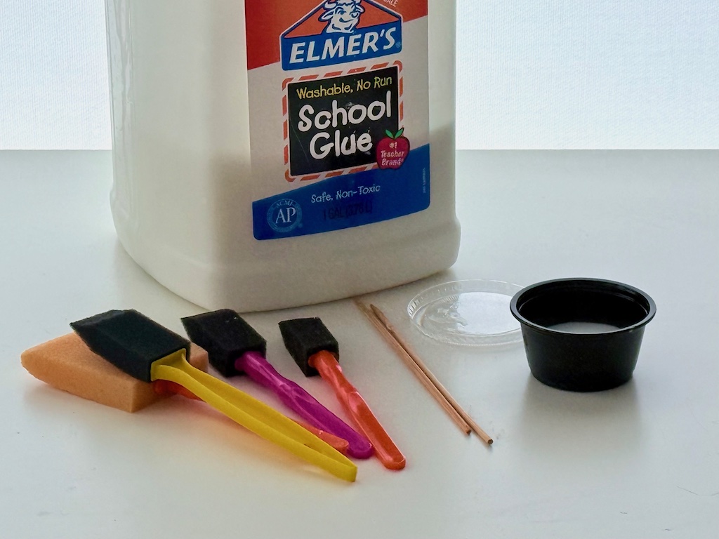 A gallon of school glue with glue tools: foam brushes, skewers, and lidded plastic sauce cups from takeout food.