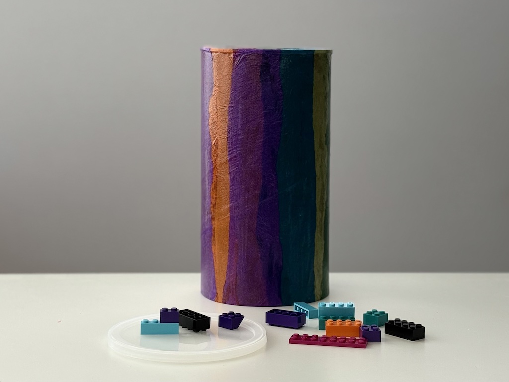 In this oatmeal container design, tissue paper strips are glued to an oatmeal container in multicolor stripes. It's a great way to use leftover tissue in making recycle crafts.