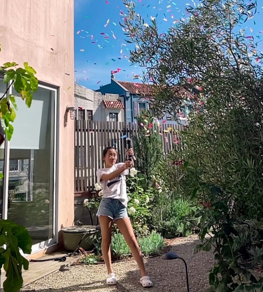 Child sets off a confetti cannon to signal the conclusion of the end of summer party.